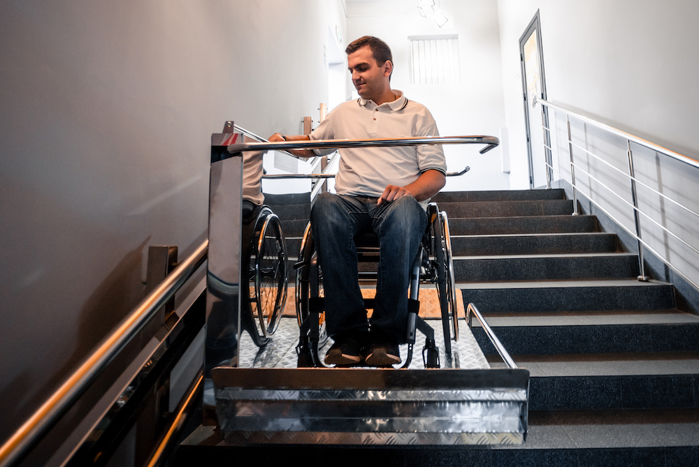 En man i rullstol som åker på en plattform hiss